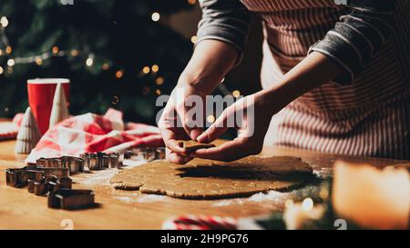 Frohe Weihnachten, Frohes neues Jahr. Lebkuchenkekse Kochen, Backen. Die junge Frau modelliert, schneidet und schnitzt Lebkuchen-Keksfiguren aus knetem Teig mit speziellen Küchenformen. Hochwertige Fotos Stockfoto