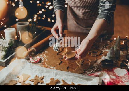 Frohe Weihnachten, Frohes neues Jahr. Lebkuchenkekse Kochen, Backen. Die junge Frau modelliert, schneidet und schnitzt Lebkuchen-Keksfiguren aus knetem Teig mit speziellen Küchenformen. Hochwertige Fotos Stockfoto