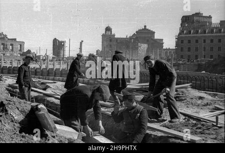 Warszawa, 1949-03. Budowa Trasy W-Z – ci¹gu komunikacyjnego Wschód-Zachód. NZ. Budowa jezdni ulicy Kapucyñskiej - uk³adanie krawê¿ników; w g³êbi gmach odbudowywanego Pa³acu Biskupów Krakowskich (P), koœció³ pw. œw. Anny wraz z dzwonnic¹ (C) oraz ruiny kamienicy przy ulicy Senatorskiej 3 i pa³acu przy ulicy Miodowej (L). mta PAP/Jerzy Baranowski Dok³adny dzieñ wydarzenia nieustalony. Warschau, März 1949. Der Bau der W-Z-Route (Ost-West-Kommunikationsleitung). Im Bild: Der Bau der Straße Kapucynska; im Hintergrund das Gebäude des Krakauer Bischofspalastes Stockfoto