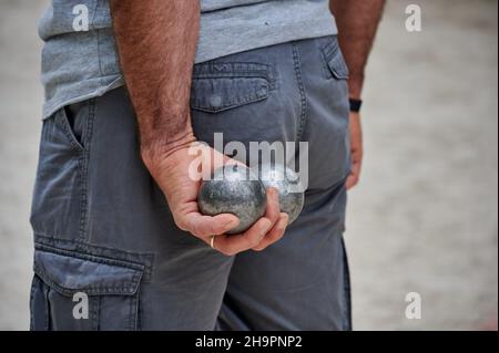 Petanque: Nahaufnahme von Bällen in den Händen eines Mannes, hinter seinem Rücken Stockfoto