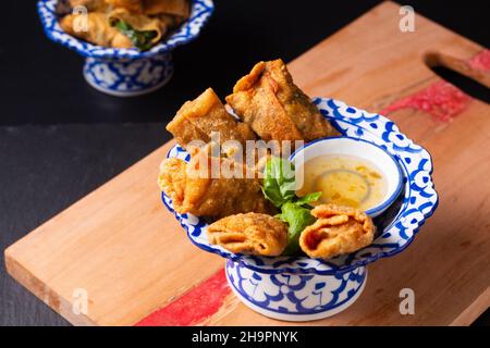 Asiatisches Speisekonzept hausgemachter frittierter Wonton mit Pflaumensoße in asiatischem Sockeltablett auf Holzbrett mit Platz für Kopien Stockfoto