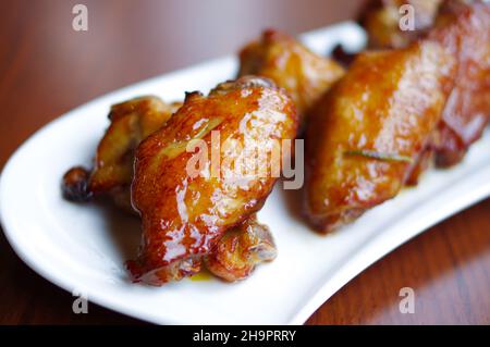 Gebackene Hähnchenflügel und Drumsticks auf weißem Teller Stockfoto