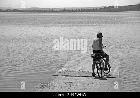 Älterer Radfahrer, der vor einer überfluteten Straße steht, Mann auf dem Fahrrad, der vor dem See steht, Bayern, Deutschland Stockfoto