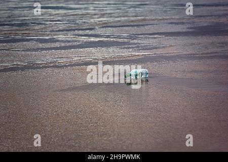 Plastikflasche, Wasserflasche der Marke Volvic, die am Strand liegt, Plastikmüll, Meeresverschmutzung, Irland Stockfoto