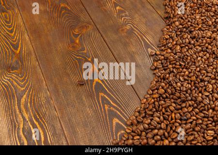 Geröstete Kaffeebohnen auf braune Holztischoberfläche gelegt Stockfoto