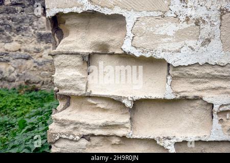 Mauerfragment mit verfallenen Kalksteinbausteinen. Zerstörerische Wirkung der Atmosphäre auf gesägte Kalksteine. Nahaufnahme. Selektiver Fokus. Stockfoto