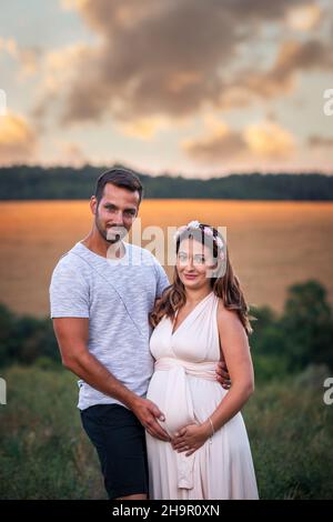 Junges Paar erwartet Baby. Eine Schwangerin mit ihrem Mann bei Sonnenuntergang Stockfoto