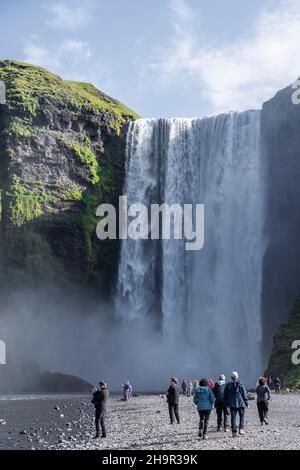 Skogafoss Wasserfall im Sommer, wenn das Wetter gut ist, Touristen neben Wasserfall in einer Schlucht, Skogar, Sudurland, Südisland, Island Stockfoto