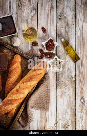 Zwei leckere traditionelle französische Baguettes aus Weizenmehl. Hausgemachtes frisches Brot auf einem Holztablett auf einem vertikalen rustikalen Hintergrund. Speicherplatz kopieren. Obere V Stockfoto