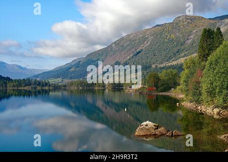 Häuser und Berge spiegeln sich in einem ruhigen See, dem Gaulartal. Norwegen Stockfoto