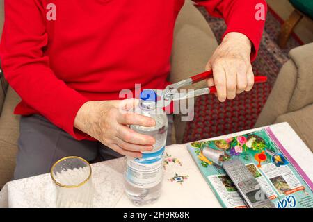 Alte Frau, Senioren, 84 Jahre, öffnet eine Wasserflasche mit Zange, München, Bayern, Deutschland Stockfoto