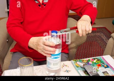 Alte Frau, Senioren, 84 Jahre, öffnet eine Wasserflasche mit Zange, München, Bayern, Deutschland Stockfoto