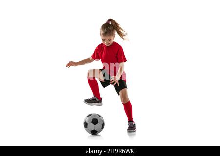 Porträt eines kleinen Mädchens, eines Kindes, das Fußball spielt, Training, Dribbling Ball auf rotem Hintergrund Stockfoto