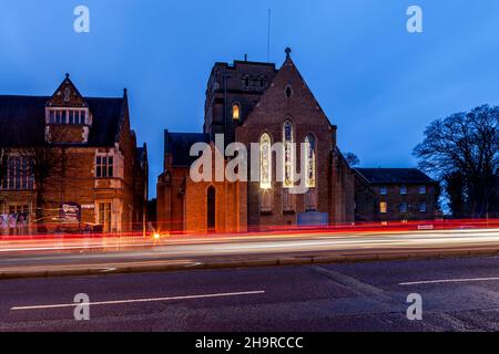 Barackstraße am späten Nachmittag mit Verkehrsbewegungen, die an der katholischen Kathedrale, Northampton, Northamptonshire, England, Großbritannien, vorbeiführen. Stockfoto