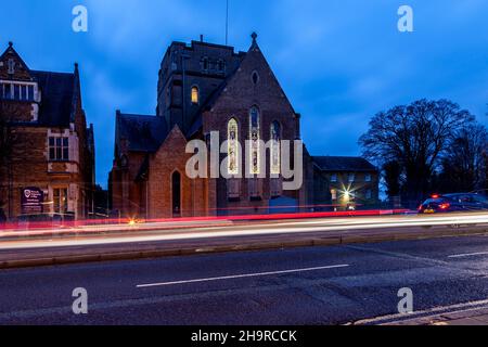 Barackstraße am späten Nachmittag mit Verkehrsbewegungen, die an der katholischen Kathedrale, Northampton, Northamptonshire, England, Großbritannien, vorbeiführen. Stockfoto