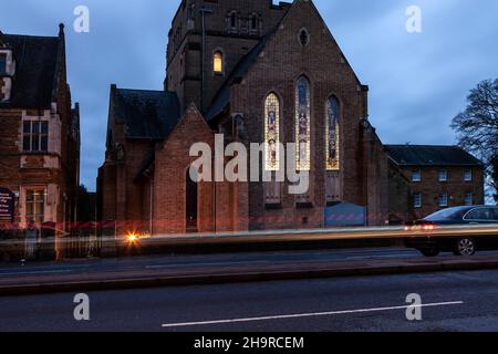 Barackstraße am späten Nachmittag mit Verkehrsbewegungen, die an der katholischen Kathedrale, Northampton, Northamptonshire, England, Großbritannien, vorbeiführen. Stockfoto