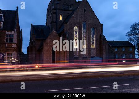 Barackstraße am späten Nachmittag mit Verkehrsbewegungen, die an der katholischen Kathedrale, Northampton, Northamptonshire, England, Großbritannien, vorbeiführen. Stockfoto