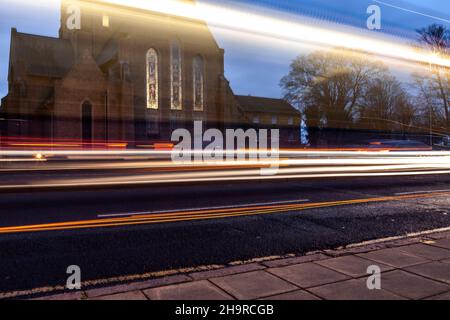 Barackstraße am späten Nachmittag mit Verkehrsbewegungen, die an der katholischen Kathedrale, Northampton, Northamptonshire, England, Großbritannien, vorbeiführen. Stockfoto