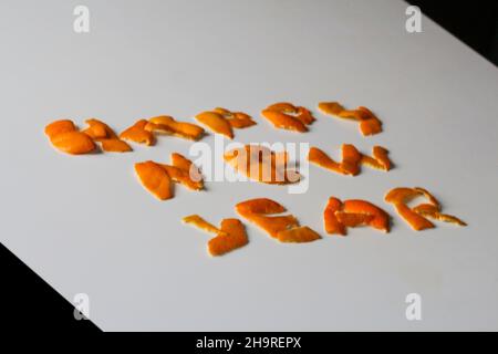 Unschärfe-Effekt Neujahrs-Wort, dargestellt durch orange trockene Schale auf grauem Hintergrund. Dekoration für Silvester, Konzept. Grußkarte. Text und DIY-Briefe. Stockfoto