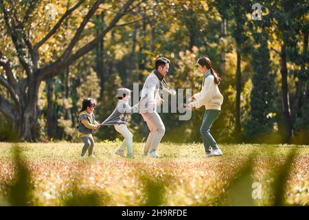 Junge asiatische Familie mit zwei Kindern, die Spaß beim Spielen im Freien im Park haben Stockfoto