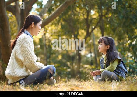 Junge asiatische Mutter und Tochter genießen ein Gespräch im Stadtpark Stockfoto