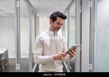 Junger Geschäftsmann, der E-Mail auf einem Tablet-Computer online in einem Startup-Büro liest Stockfoto