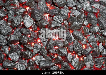 Nahaufnahme von schwarzen Steinen mit rotem Licht von unten. Stockfoto