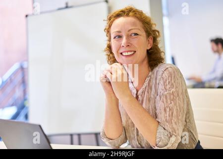 Glückliche junge Frau als Auszubildende oder Geschäftsführerin im Startup-Büro Stockfoto