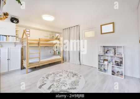 Gemütliches Kinderzimmer mit einem zweistöckigen Holzbett und einem runden Teppich Stockfoto