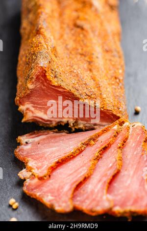 Trocken ausgehärtetes Schweinefilet auf dem Schiefertafel. Lonzino, ruckige Filet-Vorspeise auf Holzgrund. Stockfoto