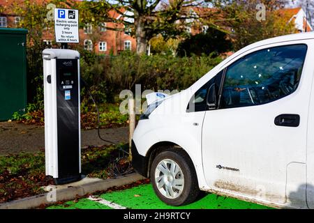 Woodbridge Suffolk UK November 28 2021: Nissan E-NV200 Elektro-Van wird an einer steckbaren Ladestation in einem öffentlichen Parkplatz in Suffolk, Großbritannien, geladen Stockfoto