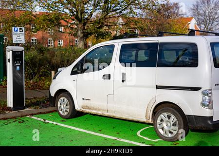 Woodbridge Suffolk UK November 28 2021: Nissan E-NV200 Elektro-Van wird an einer steckbaren Ladestation in einem öffentlichen Parkplatz in Suffolk, Großbritannien, geladen Stockfoto