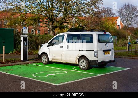 Woodbridge Suffolk UK November 28 2021: Nissan E-NV200 Elektro-Van wird an einer steckbaren Ladestation in einem öffentlichen Parkplatz in Suffolk, Großbritannien, geladen Stockfoto