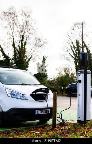 Woodbridge Suffolk UK November 28 2021: Nissan E-NV200 Elektro-Van wird an einer steckbaren Ladestation in einem öffentlichen Parkplatz in Suffolk, Großbritannien, geladen Stockfoto