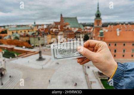 Warschau, Polen-September 20,2021. Man Tourist Hand hält Ticket zur Aussichtsplattform, verschwommene königliche Burg, Schlossplatz, Altstadt im Hintergrund. Erstaunlich Stockfoto