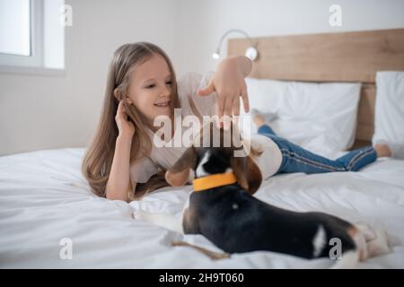 Lächelndes weibliches Kind, das den Beagle auf den Kopf klopfte Stockfoto