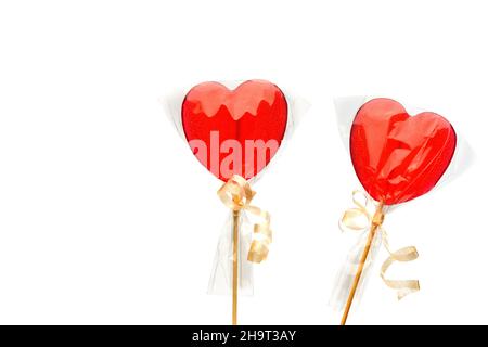 Lollipop. Zwei rote herzförmige Lutscher in transparenter Verpackung auf weißem, isoliertem Hintergrund zum Valentinstag. Isolieren. Stockfoto