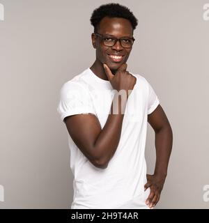 Selbstbewusster glücklicher afrikanischer Mann Millennial in weißem T-Shirt mit perfekt toothy Lächeln tragen Brillen Stockfoto