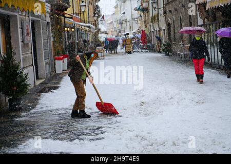 Mann, der nach einem Schneesturm Schnee von einem Fußweg entfernt. Aosta, Italien – Dezember 2021 Stockfoto