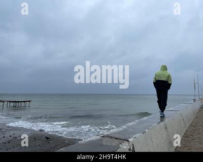 Nicht erkennbarer Mann, der auf dem Pier zum Wasser geht, Platz kopieren Stockfoto