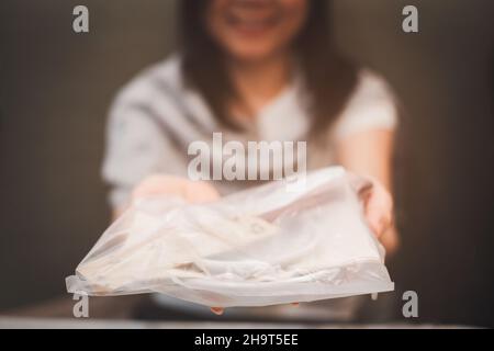 Eine Frau, die einen Teller und einen Löffel in einem Restaurant hält, ist in Plastik gewickelt, um Infektionen mit COVID-19 mit einem Lächeln zu verhindern Stockfoto