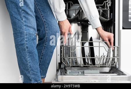 Frau macht Geschirr in der Spülmaschine zu Hause. Reinigen Sie die Teller nach dem Waschen der modernen Küche mit Geschirrspüler. Hausarbeit. Stockfoto