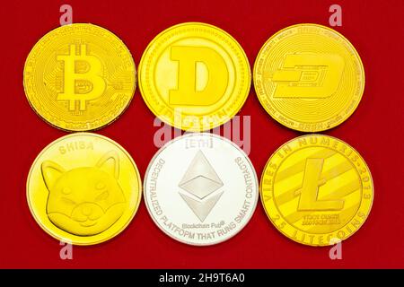 Kryptowährungsmünzen Bitcoin, Doge, Dash, Shiba, Ethereum und Litecoin auf rotem Studiohintergrund. Stockfoto
