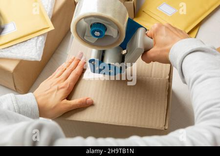 Ein Lagerarbeiter verpackt einen Karton mit einem Kassettenspender. Stockfoto