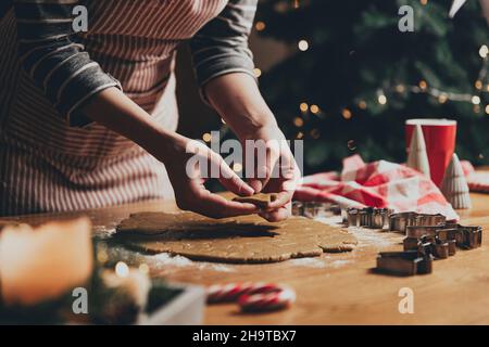 Frohe Weihnachten, Frohes neues Jahr. Lebkuchenkekse Kochen, Backen. Die junge Frau modelliert, schneidet und schnitzt Lebkuchen-Keksfiguren aus knetem Teig mit speziellen Küchenformen. Hochwertige Fotos Stockfoto