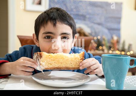 Das kleine Kind am weihnachtsmorgen am Tisch frühstückt mit Pandoro Stockfoto