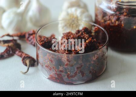 Knoblauch Chutney. Ein Gewürz aus Knoblauch und roten Chilischoten. Passt gut zu indischem Fladenbrot oder Parathen. Aufgenommen auf weißem Hintergrund Stockfoto