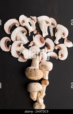Champignon und einige Pilze mit einem Messer auf einem schwarzen Holztisch in einen Korb schneiden Stockfoto