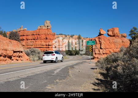 Dixie National Forest, Panguitch, Utah, USA. Weißes Auto auf der Utah State Route 12, vorbei an einem Straßenschild, das die Einfahrt zum Red Canyon markiert. Stockfoto