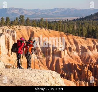 Bryce Canyon National Park, Utah, USA. Zwei Fotografen am Klippenrand schießen den Blick über das Bryce Amphitheater vom Inspiration Point, Sonnenaufgang. Stockfoto